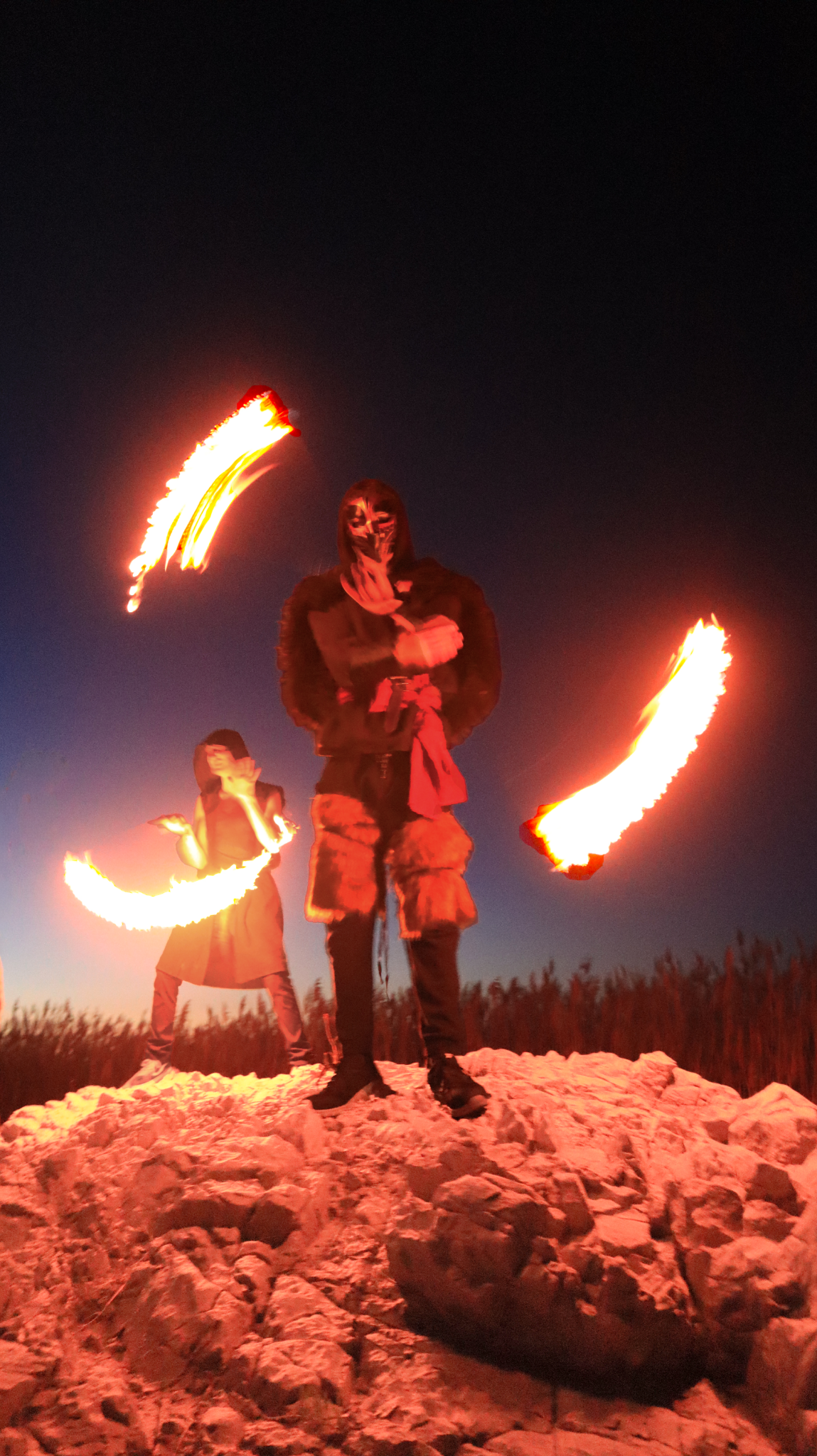 Two performers with fire on rocky terrain